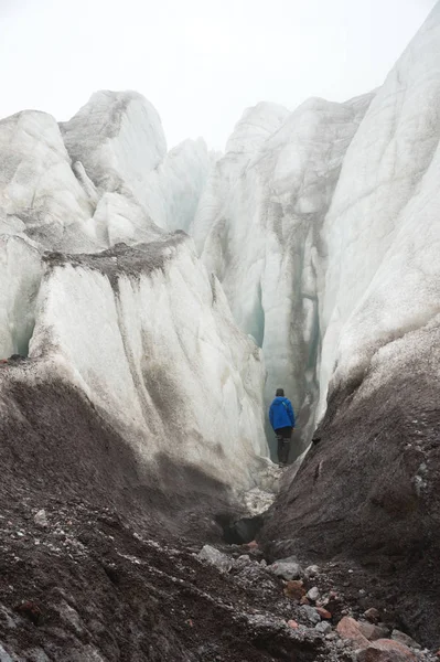 Un arrampicatore libero con una piccozza in mano si trova ai piedi del Grande Ghiacciaio accanto a un'epica crepa nella nebbia delle montagne. ostacolo insormontabile — Foto Stock