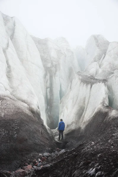 Een gratis klimmer met een ijs-bijl in zijn hand staat aan de voet van de grote gletsjer naast een epische spleet in de mist in de bergen. Onoverkomelijke hindernis — Stockfoto