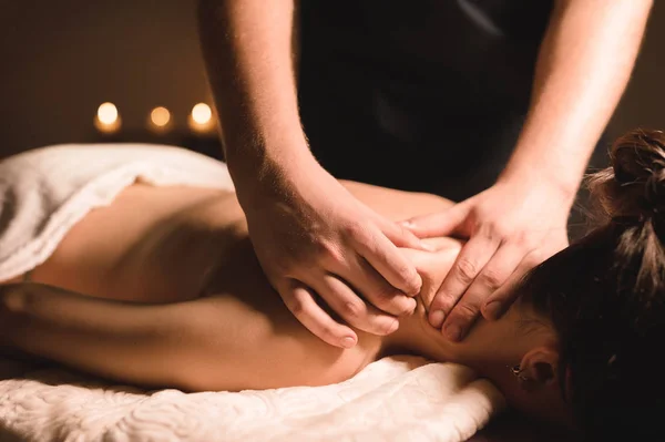 Männliche Handarbeiter tun Wellness-Massage von Schultern und Nacken für junge Mädchen in dunklen Raum — Stockfoto