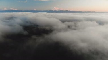 Uçan alacakaranlıkta veya şafakta bulutlar üzerinde. Uçan bir yüksek karlı dağ yönüne bulutların üzerinde. Havadan görünümü. Kuzey Kafkasya