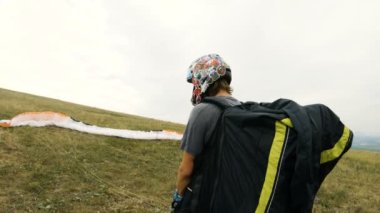 Orta atış profesyonel yamaçparaşütü pilot Kalkışa hazırlar kanat yükseltir ve paradrome kaldırdı kanat ile yürüyor