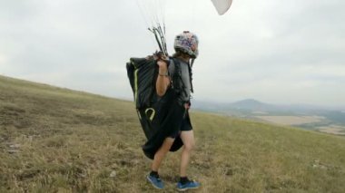 Orta atış profesyonel yamaçparaşütü pilot Kalkışa hazırlar kanat yükseltir ve paradrome kaldırdı kanat ile yürüyor