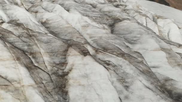 Close-up low flight over the deep cracks of a mountainous creeping glacier in 4K. Glacier powdered with yellow volcanic sand — Stock Video