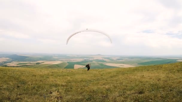 Middellange schot professionele paraglider piloot voor opstijgen bereidt verhoogt de vleugel en wandelingen met de vleugel aan de orde gesteld langs de paradrome — Stockvideo