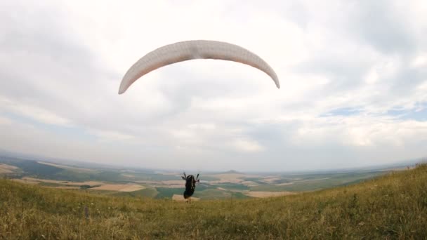 Middellange schot professionele paraglider piloot voor opstijgen bereidt verhoogt de vleugel en wandelingen met de vleugel aan de orde gesteld langs de paradrome — Stockvideo