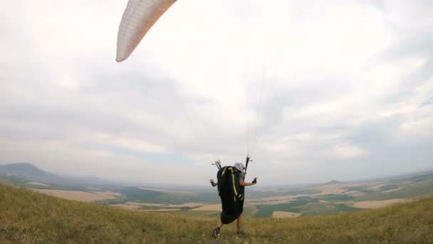 Piloto parapente profissional de tiro médio se prepara para decolagem levanta a asa e caminha com a asa levantada ao longo do paradrome — Vídeo de Stock