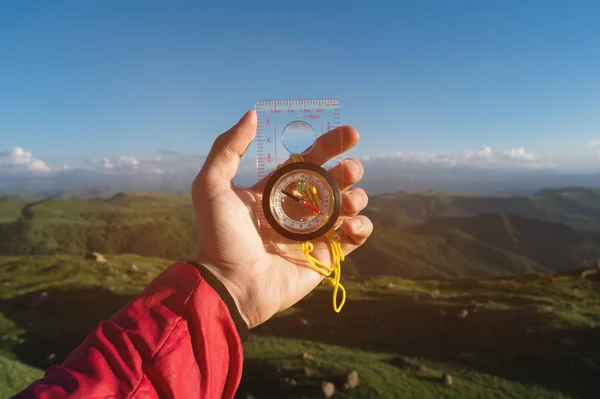 Man searching direction with a compass in his hand in the summer mountains point of view. Direction Search — Stock Photo, Image