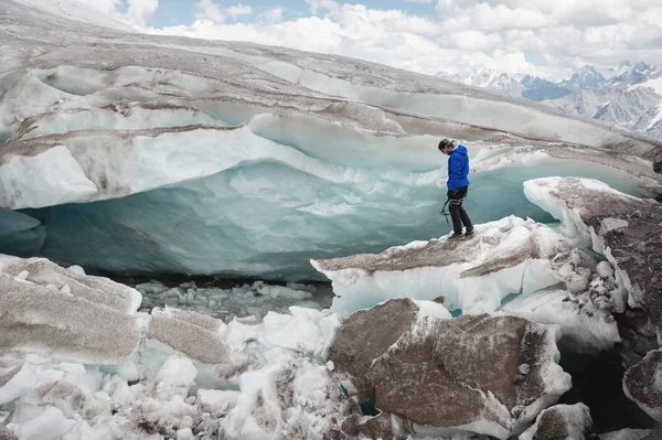 Il viaggiatore in berretto e occhiali da sole è seduto sulle montagne innevate sul ghiacciaio. Viaggiatore in un ambiente naturale — Foto Stock