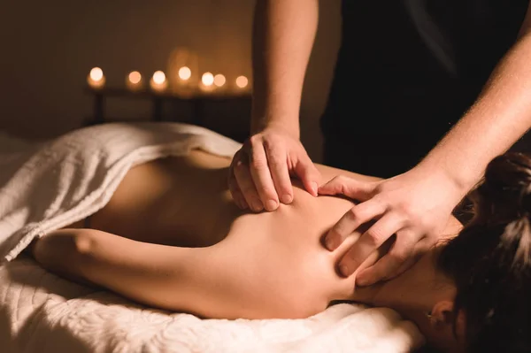 Close up Trabalhador manual masculino fazendo massagem spa para uma jovem em um quarto escuro — Fotografia de Stock