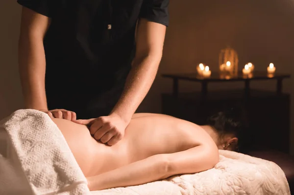 Close-up mannelijke handen doen helende massage met olie aan een jong meisje in een donkere cosmetologie kantoor. Donkere sleutel — Stockfoto