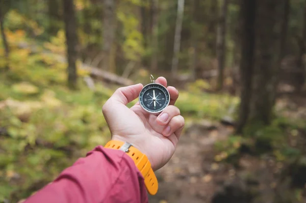 Piękne ręce mężczyzn zegarek żółty pasek posiada kompasu magnetycznego w lesie jesienią drzew iglastych. Koncepcję znalezienia się na sposób i prawdy — Zdjęcie stockowe