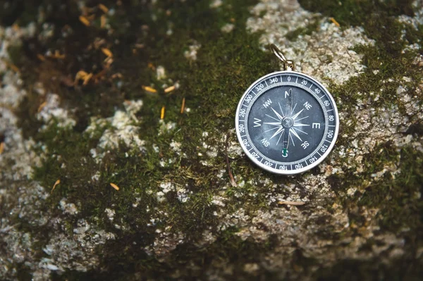 Bússola magnética com um mostrador preto em uma pedra selvagem coberta com musgo verde. O conceito de encontrar o caminho e a navegação — Fotografia de Stock