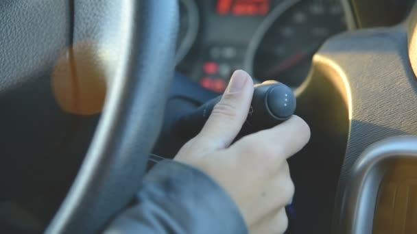 En närbild av en flicka vänder på ratten spaken torkarna. Kvinna som kör bil. Flickor hand på växeln — Stockvideo