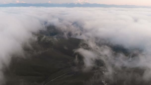 Flygande över molnen i skymningen eller gryningen. Flygande ovan molnen i riktning mot en höga snötäckta berg. Flygfoto. Norra Kaukasus — Stockvideo