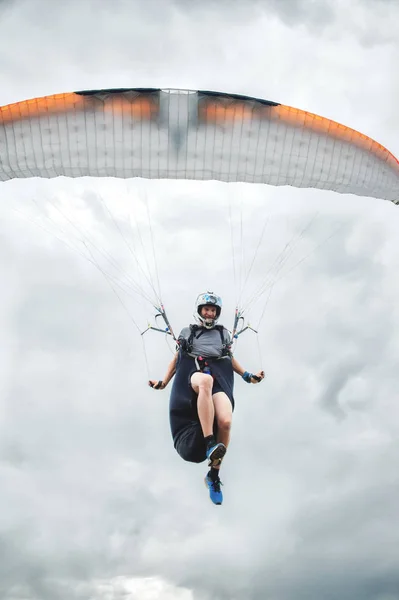 Close-up professional paraglider with a cocoon on his shoulders flies over the camera in a jump. Paraglider sport concept