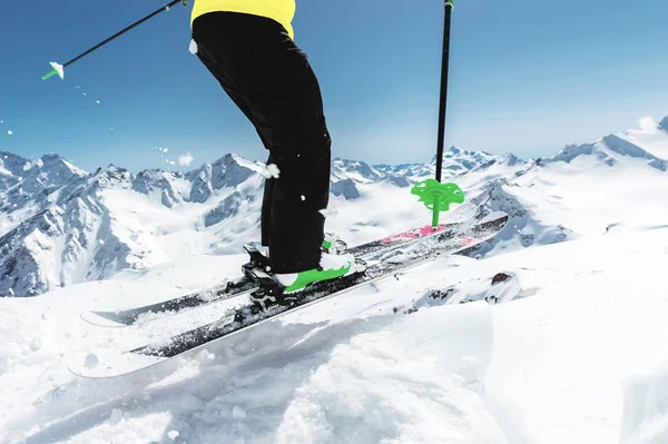 Un skieur en équipement sportif complet saute dans l'abîme depuis le sommet du glacier sur fond de ciel bleu et de montagnes enneigées du Caucase. Vue de l'arrière. Région d'Elbrus — Photo