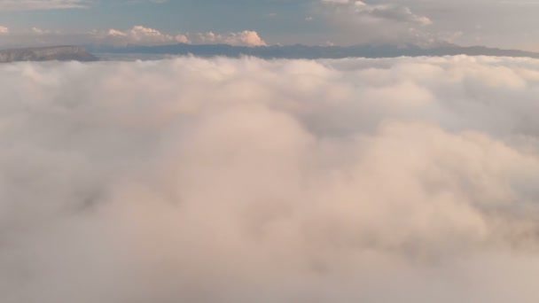 Volare sulle nuvole al tramonto o all'alba. Volare sopra le nuvole in direzione di un'alta montagna innevata. Vista aerea. Caucaso settentrionale — Video Stock