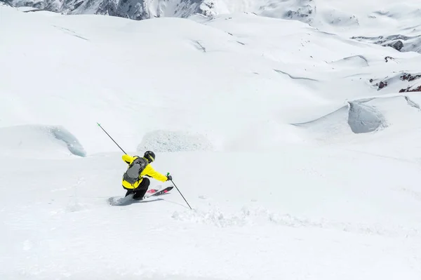 A skier at speed rides on a snowy slope freeride. The concept of winter extreme sports — Stock Photo, Image