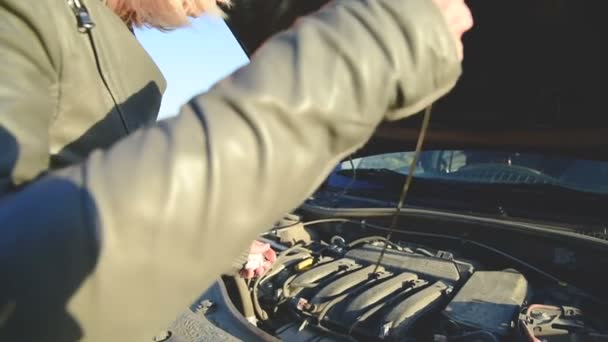 La chica en la carretera comprueba el nivel de aceite del motor en el motor. Primer plano de la mano de las niñas para alcanzar el control de aceite de varilla de inmersión — Vídeos de Stock