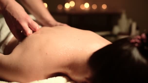 Gros plan mains masculines faisant massage curatif à l'huile à une jeune fille dans un bureau de cosmétologie sombre. Clé sombre — Video