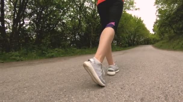 Close-up Piernas de chica delgada antes de correr en el bosque. Movimiento de ángulo bajo alrededor del objeto — Vídeo de stock