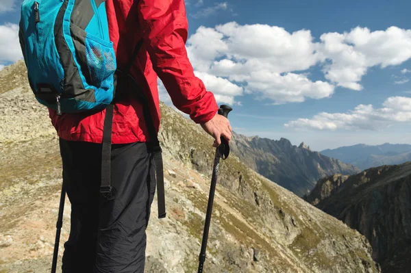 Tělo člověka s batohem a trekingových holí stojí na vrcholu skály proti pozadí skalnatých údolí vysokou v horách. Koncepce cestovního ruchu a snadný trekking v horách venkovní — Stock fotografie