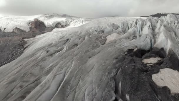 Närbild låg flygning över djupa sprickor i en bergig krypande glaciär i 4k. Glaciären pulverform med gula vulkanisk sand — Stockvideo