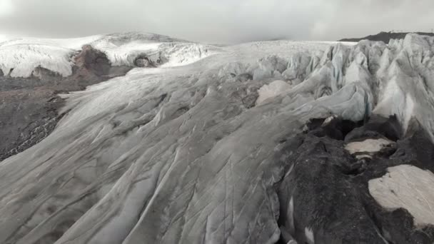 Close-up voo baixo sobre as rachaduras profundas de uma geleira rastejante montanhosa em 4K. Glaciar em pó com areia vulcânica amarela — Vídeo de Stock