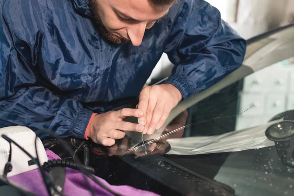 Närbild av Automobile glasmästare arbetare fastställande och reparera vindrutan eller vindrutan på en bil i auto service station garage — Stockfoto