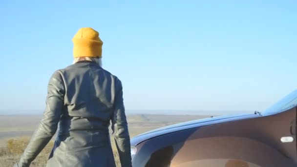 A blonde girl finding a fault in her SUV gets out of the car and opens the hood. Outside view — Stock Video