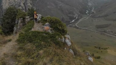 Şapkalı kız fotoğrafçı sarışın dağlarda bir kamera ile yürür. Chegem gorge Kuzey Kafkasya