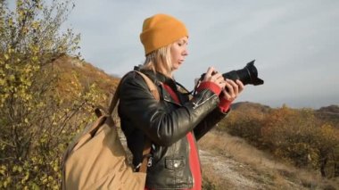 Yakın çekim sarı şapkalı çekici bir beyaz kız onu Slr kamera açık havada sonbaharda çıkartıyor. Eserlerinde gülümseyen kız