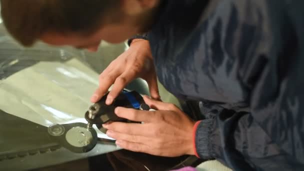 Primer plano de un hombre profesionalmente en el taller dedicado a la eliminación de grietas en el parabrisas del coche. Trabajo de llenadora al vacío — Vídeos de Stock