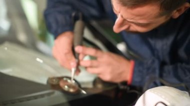 Bir erkekte profesyonel atölye Close-up arabanın ön cam üzerinde çatlaklar giderilmesinde nişanlı. Polimer drenaj sondaj