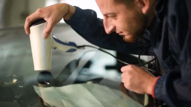 Bir erkekte profesyonel atölye Close-up arabanın ön cam üzerinde çatlaklar giderilmesinde nişanlı. Hava kurutma