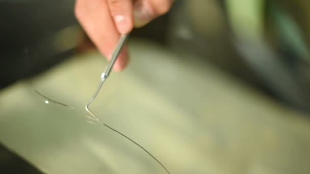 Close-up of a man professionally in the workshop engaged in eliminating cracks on the windshield of the car. Filling the crack with polymer — Stock Video