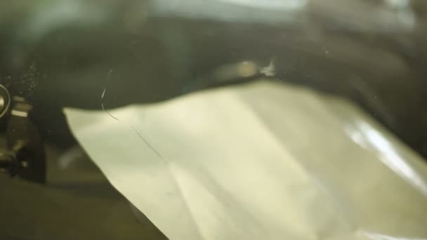 Close-up of a man professionally in the workshop engaged in eliminating cracks on the windshield of the car. Filling the crack with polymer — Stock Video