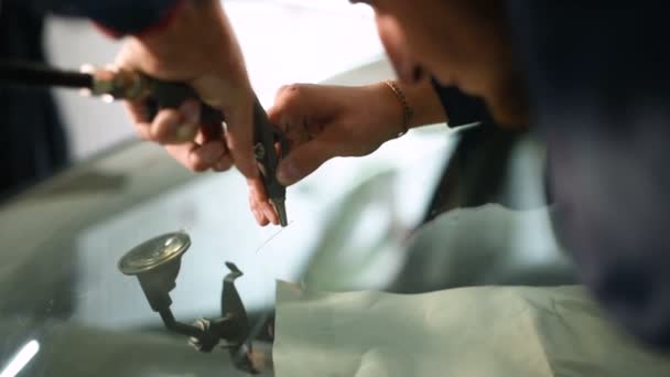 자동차의 앞 유리에 균열을 제거에 종사 하는 워크샵에 전문적으로 남자의 클로즈업. 건조 공기 — 비디오