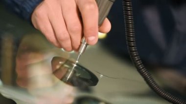Bir erkekte profesyonel atölye Close-up arabanın ön cam üzerinde çatlaklar giderilmesinde nişanlı. Polimer drenaj sondaj