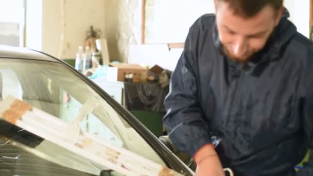 Nahaufnahme eines Mannes, der professionell in der Werkstatt damit beschäftigt ist, Risse an der Windschutzscheibe des Autos zu beseitigen. Reinigung von überschüssigem Polymer — Stockvideo