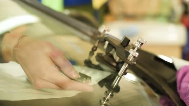 Primer plano de un hombre profesionalmente en el taller dedicado a la eliminación de grietas en el parabrisas del coche. Trabajo de llenadora al vacío — Vídeos de Stock