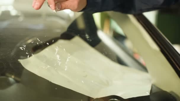Крупный план человека, профессионально работающего в мастерской, занимающегося устранением трещин на лобовом стекле автомобиля. Заполнение трещины полимером — стоковое видео