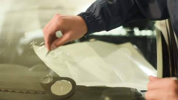 Közeli kép: egy ember szakmailag a műhelyben, részt vesz a szélvédő az autó repedések megszüntetése. Felesleges polimer tisztítása — Stock videók