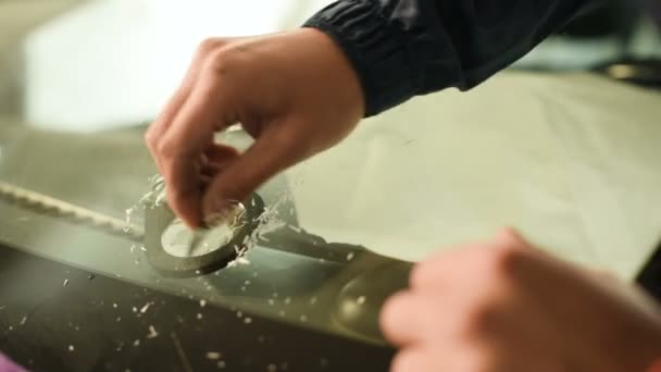 Gros plan d'un homme professionnellement engagé dans l'atelier pour éliminer les fissures sur le pare-brise de la voiture. Purification de l'excès de polymère — Video