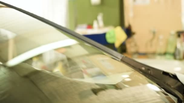 Close-up de um homem profissionalmente na oficina envolvida na eliminação de rachaduras no pára-brisas do carro. Enchendo a rachadura com polímero — Vídeo de Stock