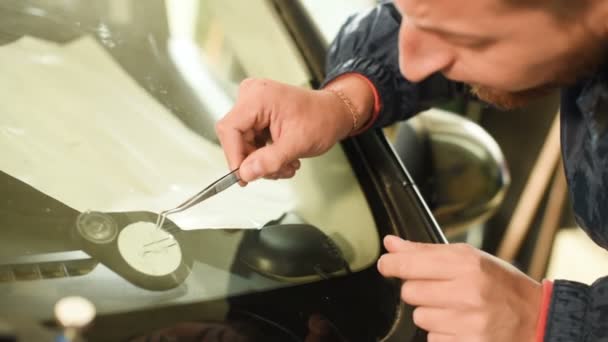 Nahaufnahme eines Mannes, der professionell in der Werkstatt damit beschäftigt ist, Risse an der Windschutzscheibe des Autos zu beseitigen. Füllen des Risses mit Polymer — Stockvideo