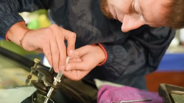 Primo piano di un uomo professionalmente in officina impegnato nell'eliminazione delle crepe sul parabrezza dell'auto. Lavoro di riempimento sottovuoto — Video Stock