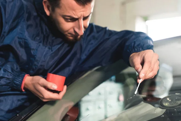 Närbild av Automobile glasmästare arbetare fastställande och reparera vindrutan eller vindrutan på en bil i auto service station garage — Stockfoto