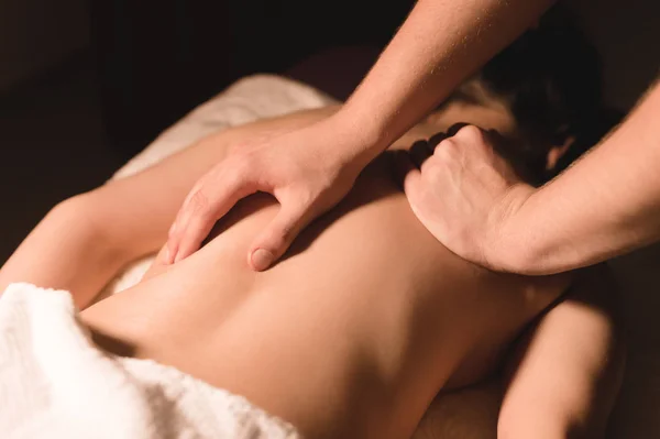 Närbild manliga händer gör healing massage med olja till en ung flicka i en mörk kosmetologi kontor. Mörka nyckel — Stockfoto