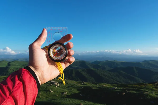 Man searching direction with a compass in his hand in the summer mountains point of view. Direction Search — Stock Photo, Image